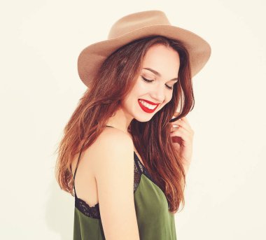 Genç şık kız modeli rahat yaz yeşil giysiler ve kırmızı dudaklı beyaz duvara yakın poz, kahverengi şapka