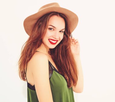 Genç şık kız modeli rahat yaz yeşil giysiler ve kırmızı dudaklı beyaz duvara yakın poz, kahverengi şapka