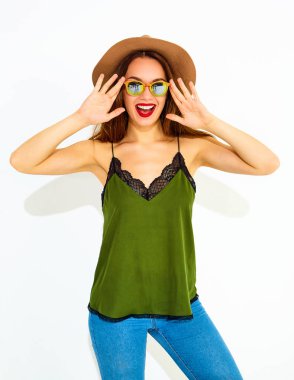 Genç şık kız modeli rahat yaz yeşil giysiler ve kırmızı dudaklı beyaz duvara yakın poz, kahverengi şapka