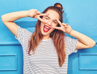 Gündelik yaz kıyafetleri kırmızı dudaklar, mavi duvara yakın poz ile genç şık kız modeli. Göz kırpıyor