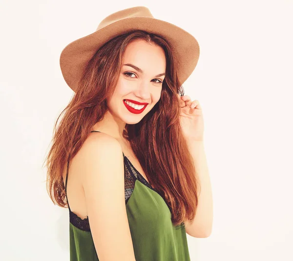 Genç şık kız modeli rahat yaz yeşil giysiler ve kırmızı dudaklı beyaz duvara yakın poz, kahverengi şapka