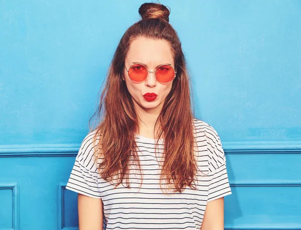 Gündelik yaz kıyafetleri kırmızı dudaklar, mavi duvara yakın poz ile genç şık kız modeli