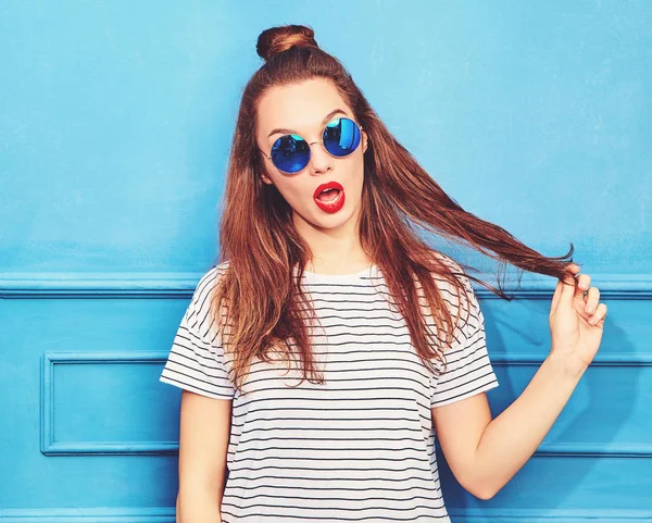 年轻时尚的女孩在休闲夏天的衣服 红色的嘴唇 摆在蓝色的墙壁附近的模型 玩弄她的头发 — 图库照片