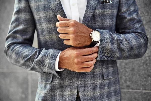 ファッションモデル実業家通りの背景に灰色の壁に近いポーズ エレガントなの市松模様のスーツを着てください 高級時計の手首にメトロ セクシャル — ストック写真