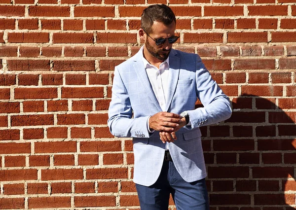 セクシーなハンサムな実業家ファッションモデルの肖像画通りの背景のレンガの壁に近いポーズ エレガントなの青いスーツを着てください メトロ セクシャル — ストック写真