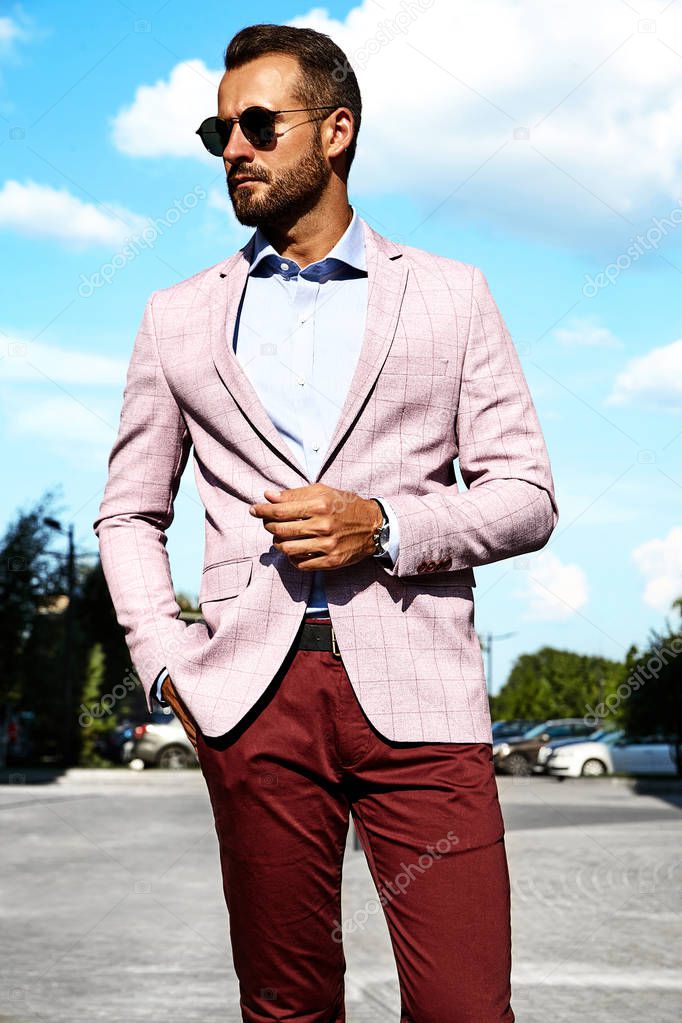 Portrait of sexy handsome fashion businessman model dressed in elegant suit posing on street background. Metrosexual