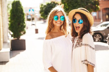 İki genç şık hippi esmer ve sarışın Bayan modelleri yaz güneşli günde sokak arka plan üzerinde poz beyaz hipster giysileri moda portre. Delirmek