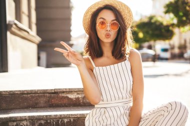 Yaz hipster giysileri sokak arka merdivenlerde oturan güzel şirin sarışın genç modeli. Hava öpücük vermek ve barış işareti gösterilen