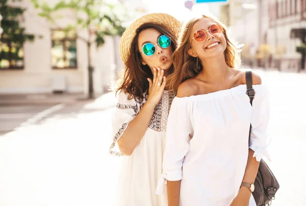 İki genç şık hippi esmer ve sarışın Bayan modelleri yaz güneşli günde sokak arka plan üzerinde poz beyaz hipster giysileri moda portre. Delirmek