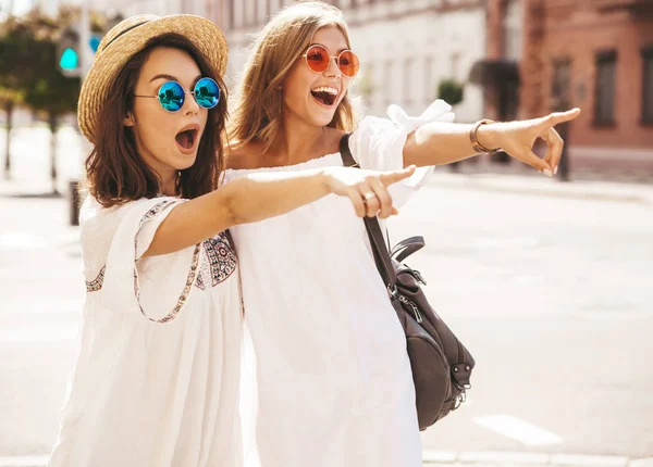 İki yaz güneşli günde sokak arka plan üzerinde poz beyaz hipster giysili genç şık hippi esmer ve sarışın Bayan modelleri moda. Dükkanı satış işaret