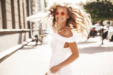 Güzel şirin sarışın genç modeli güneş gözlüğü sokakta çalışan yaz hipster beyaz elbiseli hiç makyaj ile. Civarında ve koşma