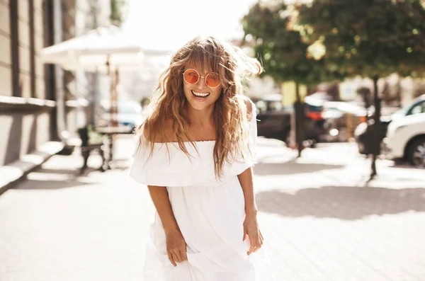 美しいかわいい笑顔金髪ティーンエイ ジャー モデルのサングラスの通りに実行している夏流行に敏感な白いドレスの化粧品 振り向いてください — ストック写真