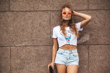 Güzel şirin sarışın genç model makyaj sokak duvarının yakınında poz yaz hipster beyaz giysileri olmadan. Renkli kokteyl şişeden içme