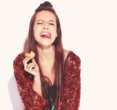 Güzel beyaz gülümseyen hipster esmer kadın modelinde parlak parlak yaz şık ceket ve yeşil elbise beyaz arka plan üzerinde izole yansıtan. Fransız acıbadem kurabiyesi yeme ve dilini gösteren