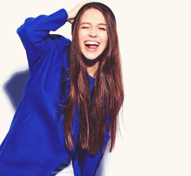 Güzel gülümseyen hipster esmer kadın modeli üzerinde beyaz izole şık mavi palto. Bir göz kırpışı yapma