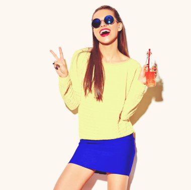 esmer kadın kız rahat hipster yaz renkli giysileri beyaz saman güneş gözlüğü ile şişe soda içme ve barış işaret gösteren izole kırmızı dudaklar ile gülümseyen güzel deli portresi