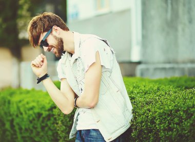 Komik gülümseyen hipster yakışıklı çocuk güneş gözlüğü sokakta şık kumaş