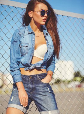 Portresi komik deli sihir şık gülümseyen güzel genç kadın model parlak hipster yaz casual kot elbise demir ızgara ve mavi arkasındaki sokakta poz gökyüzü