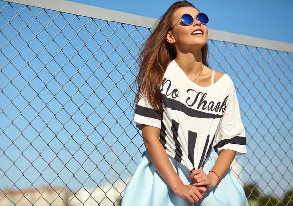 Komik deli sihir şık gülümseyen güzel genç kadın model parlak hipster yaz rahat giysileri demir ızgara ve mavi arkasındaki sokakta poz portresi gökyüzü