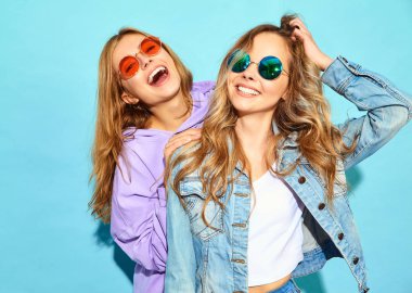 İki genç güzel sarışın gülümseyen hippi kız trendy yaz giysileri. Seksi kaygısız kadın güneş gözlüğü mavi duvarının yakınında poz. Olumlu modelleri
