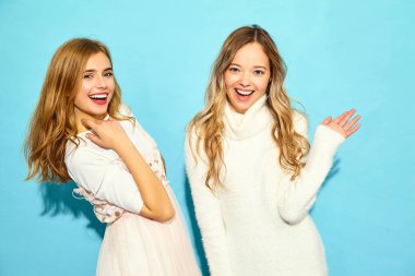 İki genç güzel gülümseyen hippi kız trendy yaz giysileri beyaz. Seksi kaygısız kadın mavi duvara yakın poz. Olumlu modelleri