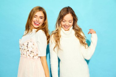 İki genç güzel gülümseyen hippi kız trendy yaz giysileri beyaz. Seksi kaygısız kadın mavi duvara yakın poz. Olumlu modelleri
