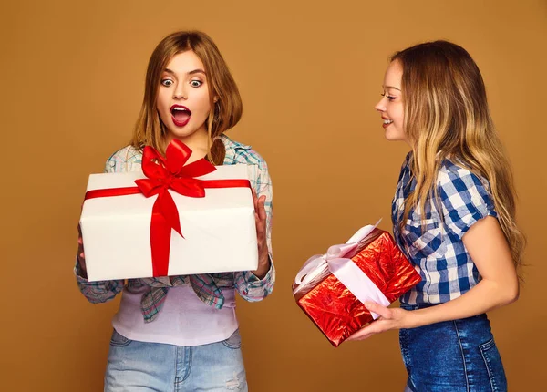 圣诞节 两个穿着时尚服装的微笑的美女 女孩在金色背景上摆姿势 带有大礼品盒的模型 玩得开心 准备庆祝 最好的朋友的明亮假期 — 图库照片