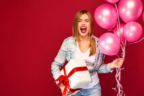 穿着嬉皮士服装的兴奋的年轻女孩 妇女模型庆祝和举行箱子与礼物礼物和粉红色的气球在红色背景 圣妇女节 新年快乐 生日模拟节日派对概念 — 图库照片