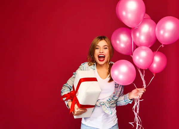 穿着嬉皮士服装的兴奋的年轻女孩 妇女模型庆祝和举行箱子与礼物礼物和粉红色的气球在红色背景 圣妇女节 新年快乐 生日节日派对 — 图库照片