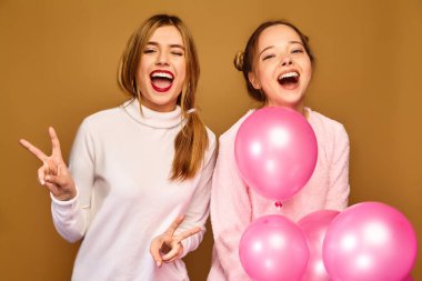 İki genç kız beyaz şirin giysiler heyecanlı. Bayan modelleri altın arka plan üzerinde pembe hava balonlu. St. kadınlar günü; Mutlu yeni yıl; Doğum günü tatil partisi