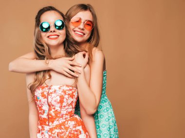 İki genç güzel sarışın gülümseyen hippi kız trendy yaz elbise. Seksi kaygısız kadın güneş gözlüğü altın duvarının yakınında poz. Sarılma pozitif sevimli modelleri