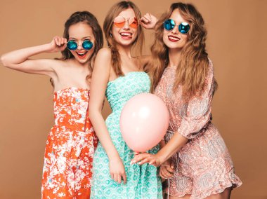 Üç genç güzel gülümseyen hippi kız trendy yaz casual elbiseler. Seksi kaygısız kadın mavi duvara yakın poz. Retro kamera resim çekme