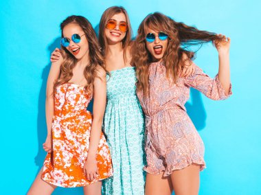 Üç genç güzel gülümseyen hippi kız trendy yaz casual elbise ve güneş gözlüğü. Seksi kaygısız kadın mavi duvara yakın poz. Delirmek olumlu modelleri