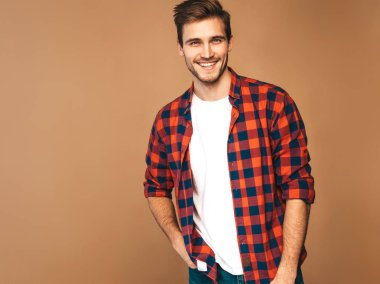 Portre yakışıklı gülümseyen şık hipster lumbersexual işadamı model kırmızı kareli gömlek giymiş. Moda adam. Altın arka plan üzerinde poz