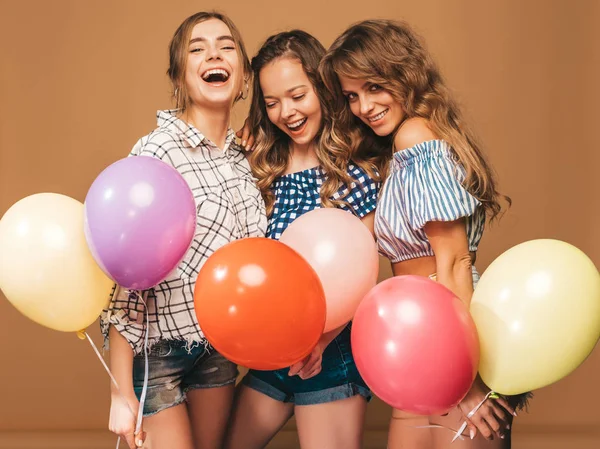 三个面带微笑的美女穿着格子衬衫夏装 女孩在金色背景上摆姿势 带有五颜六色的气球的模型 玩得开心 准备庆祝生日或节日聚会 — 图库照片