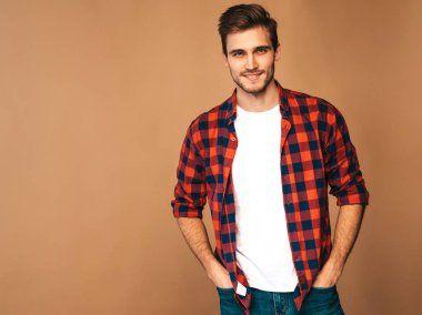 Portre yakışıklı gülümseyen şık hipster lumbersexual işadamı model kırmızı kareli gömlek giymiş. Altın arka plan üzerinde poz moda adam