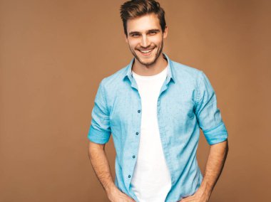 Portre yakışıklı gülümseyen şık hipster lumbersexual işadamı modeli mavi gömlek elbise giymiş. Altın arka plan üzerinde poz moda adam