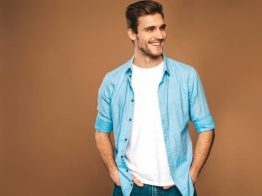Portre yakışıklı gülümseyen şık hipster lumbersexual işadamı modeli mavi gömlek elbise giymiş. Altın arka plan üzerinde poz moda adam