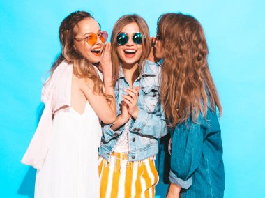 Üç genç güzel gülümseyen hippi kız trendy yaz rahat kıyafetler. Seksi kadın sırlarını, dedikodu paylaşır. Mavi izole. Sürpriz yüz duygular