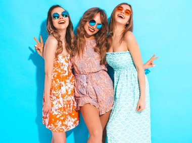 Üç genç güzel gülümseyen hippi kız trendy yaz renkli elbiseler. Mavi izole güneş gözlüklü seksi kaygısız kadın. Delirmek olumlu modelleri