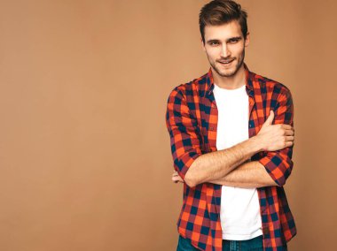 Portre yakışıklı gülümseyen şık hipster lumbersexual işadamı model kırmızı kareli gömlek giymiş. Altın arka plan üzerinde poz moda adam. Çapraz kollar