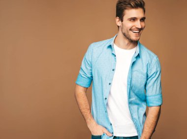 Portre yakışıklı gülümseyen şık hipster lumbersexual işadamı modeli mavi gömlek elbise giymiş. Altın arka plan üzerinde poz moda adam