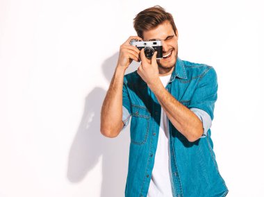 Gülümseyen yakışıklı yaz hipster kot elbise giyen portresi. Eski vintage fotoğraf makinesi modeli erkek alarak resmi. Beyaz izole