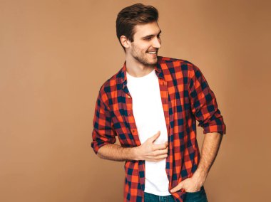 Portre yakışıklı gülümseyen şık hipster lumbersexual işadamı model kırmızı kareli gömlek giymiş. Altın arka plan üzerinde poz moda adam