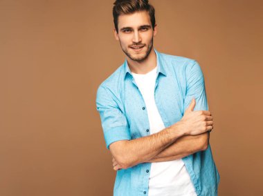 Portre yakışıklı gülümseyen şık hipster lumbersexual işadamı modeli mavi gömlek elbise giymiş. Altın arka plan üzerinde poz moda adam. Çapraz kollar