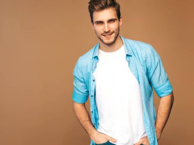 Portre yakışıklı gülümseyen şık hipster lumbersexual işadamı modeli mavi gömlek elbise giymiş. Altın arka plan üzerinde poz moda adam