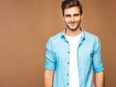 Portre yakışıklı gülümseyen şık hipster lumbersexual işadamı modeli mavi gömlek elbise giymiş. Altın arka plan üzerinde poz moda adam