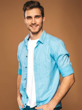 Portre yakışıklı gülümseyen şık hipster lumbersexual işadamı modeli mavi gömlek elbise giymiş. Altın arka plan üzerinde poz moda adam