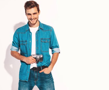 Gülümseyen yakışıklı yaz hipster kot elbise giyen portresi. Eski vintage fotoğraf makinesi modeli erkek alarak resmi. Beyaz izole