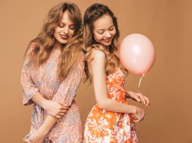 İki güzel kadın yaz hipster gülümseyen Giydir. Altın arka plan üzerinde poz kızlar. Modelleri renkli hava balonları ile. Eğleniyor, kutlama Doğum günü veya tatil parti için hazır